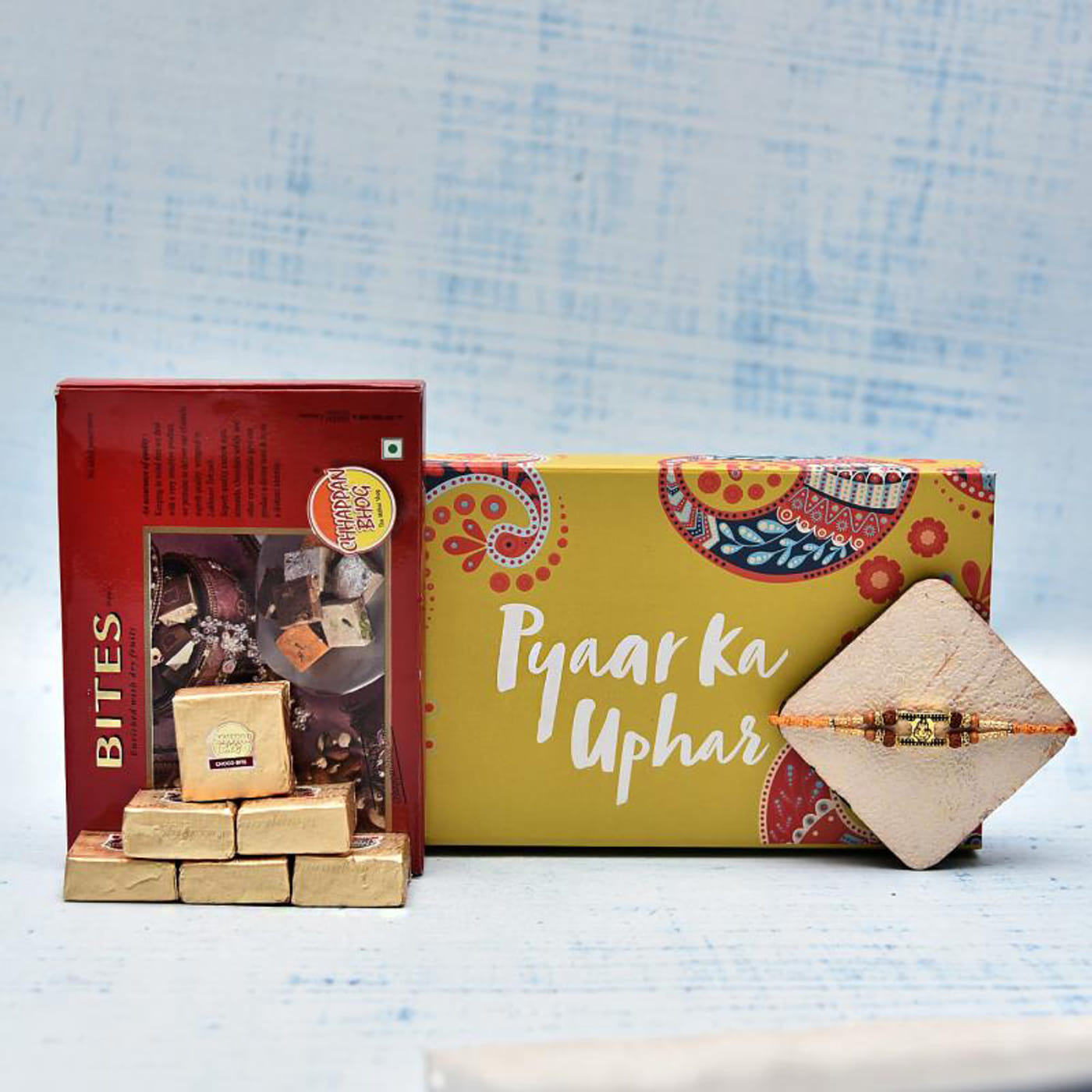 metal ganesha rudraksh rakhi with 6 pcs mewa bites in a gift box
