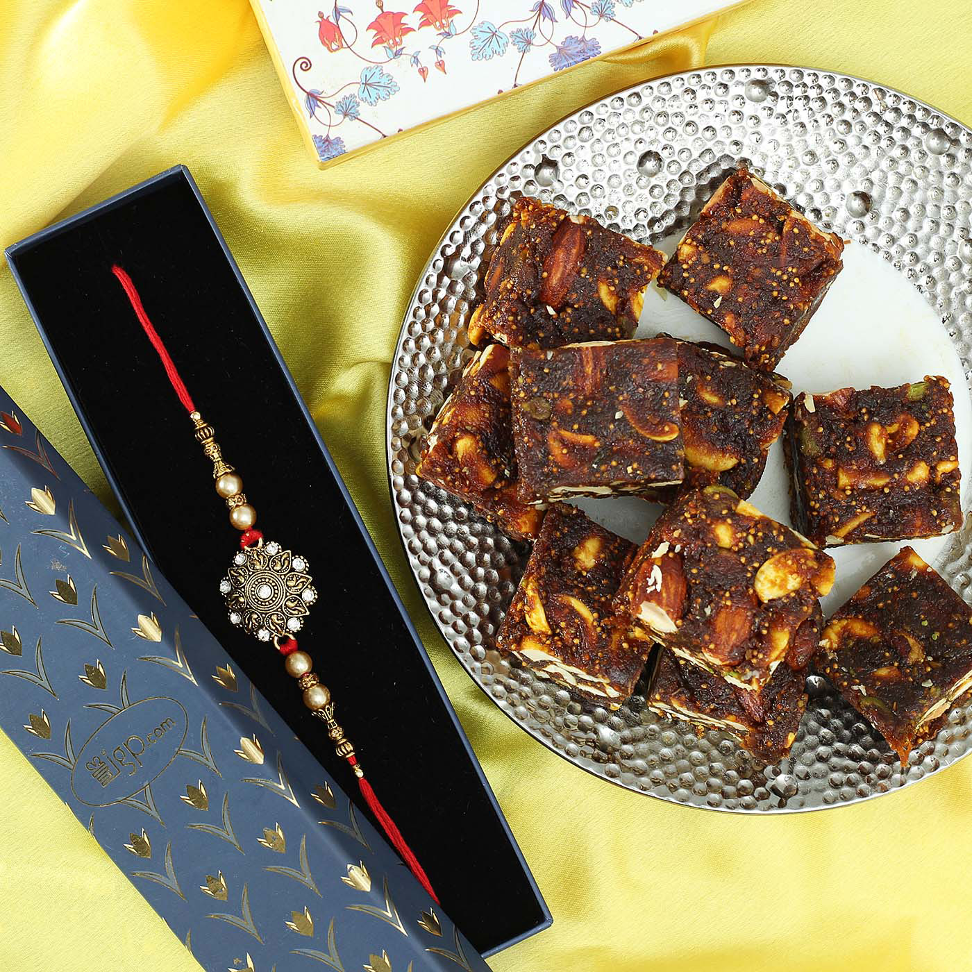 metallic-flower-dial-rakhi-with-sugar-free-anjeer-dry-fruit-barfi